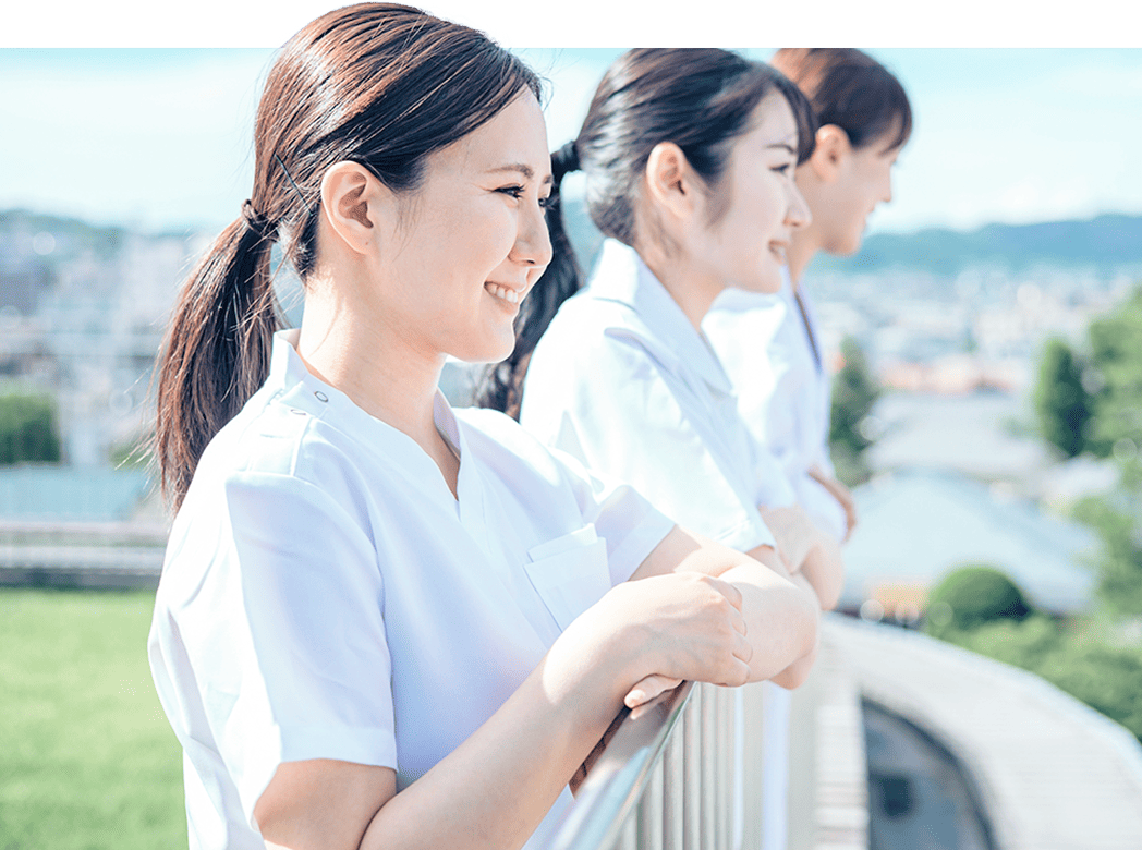 白い制服を着た3人の女性が、並んで景色を見ている様子。