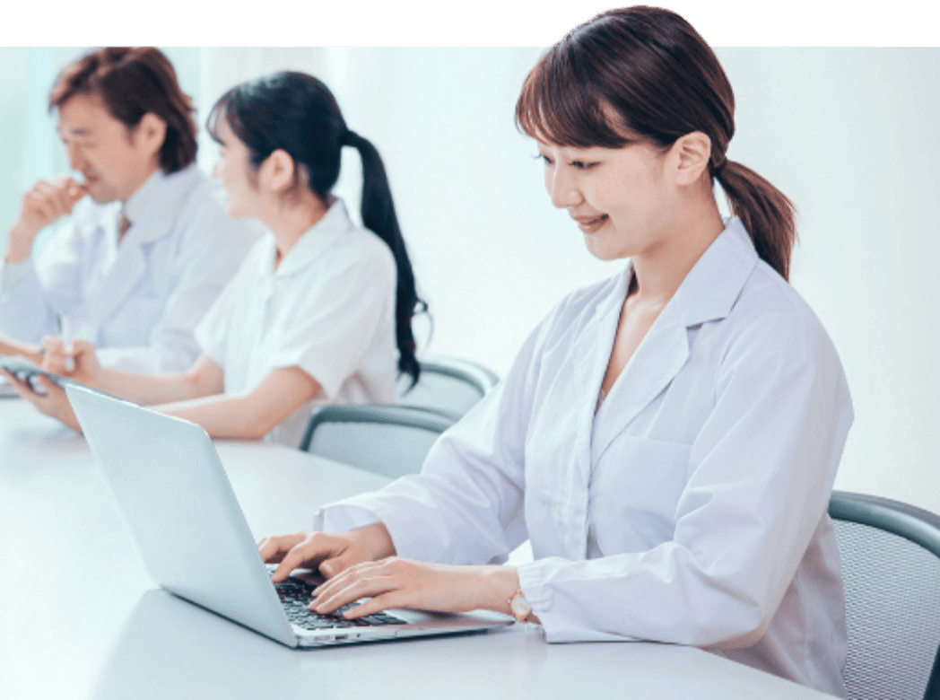 会議室で、パソコンで作業する女性医師。