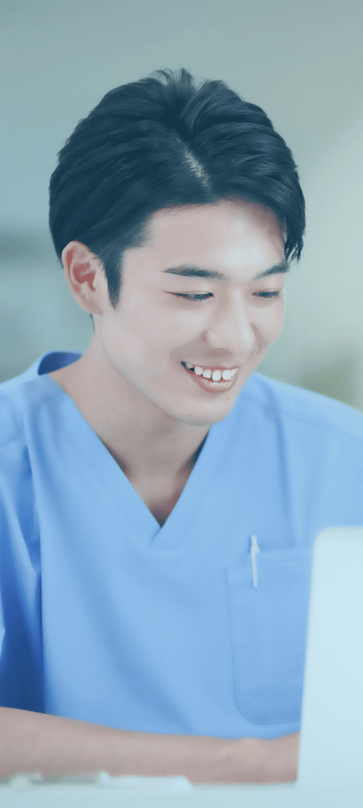 笑顔でパソコン作業をする男性医療従事者