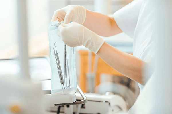 歯科衛生士が滅菌パックに入った歯科治療器具を準備している様子