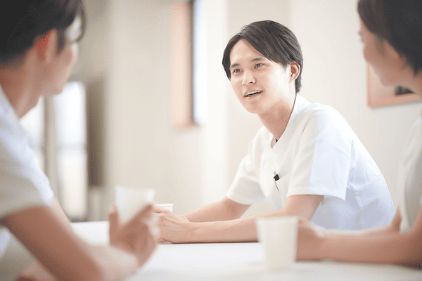 休憩中の三人の医療従事者が笑顔で会話をしている様子。