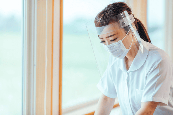 フェイスシールドとマスクを着用した女性看護師が仕事をしている様子