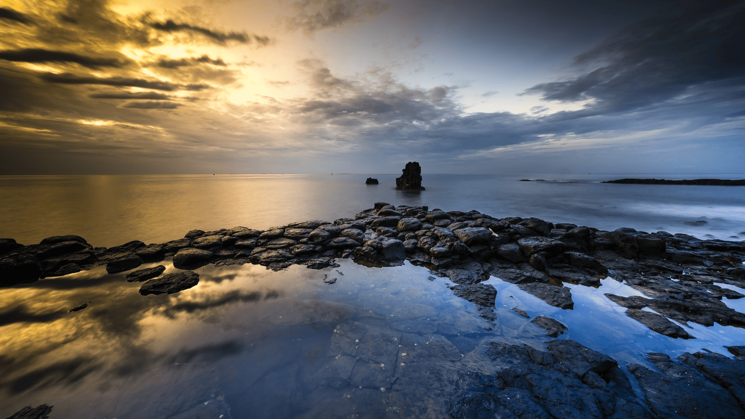 夕焼けと雲が美しい、岩礁と穏やかな海の風景