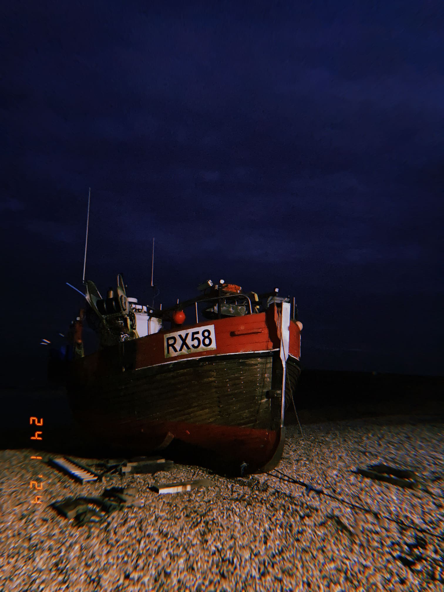 夜の砂利浜に置かれた赤い漁船RX58（ヘイスティングス）