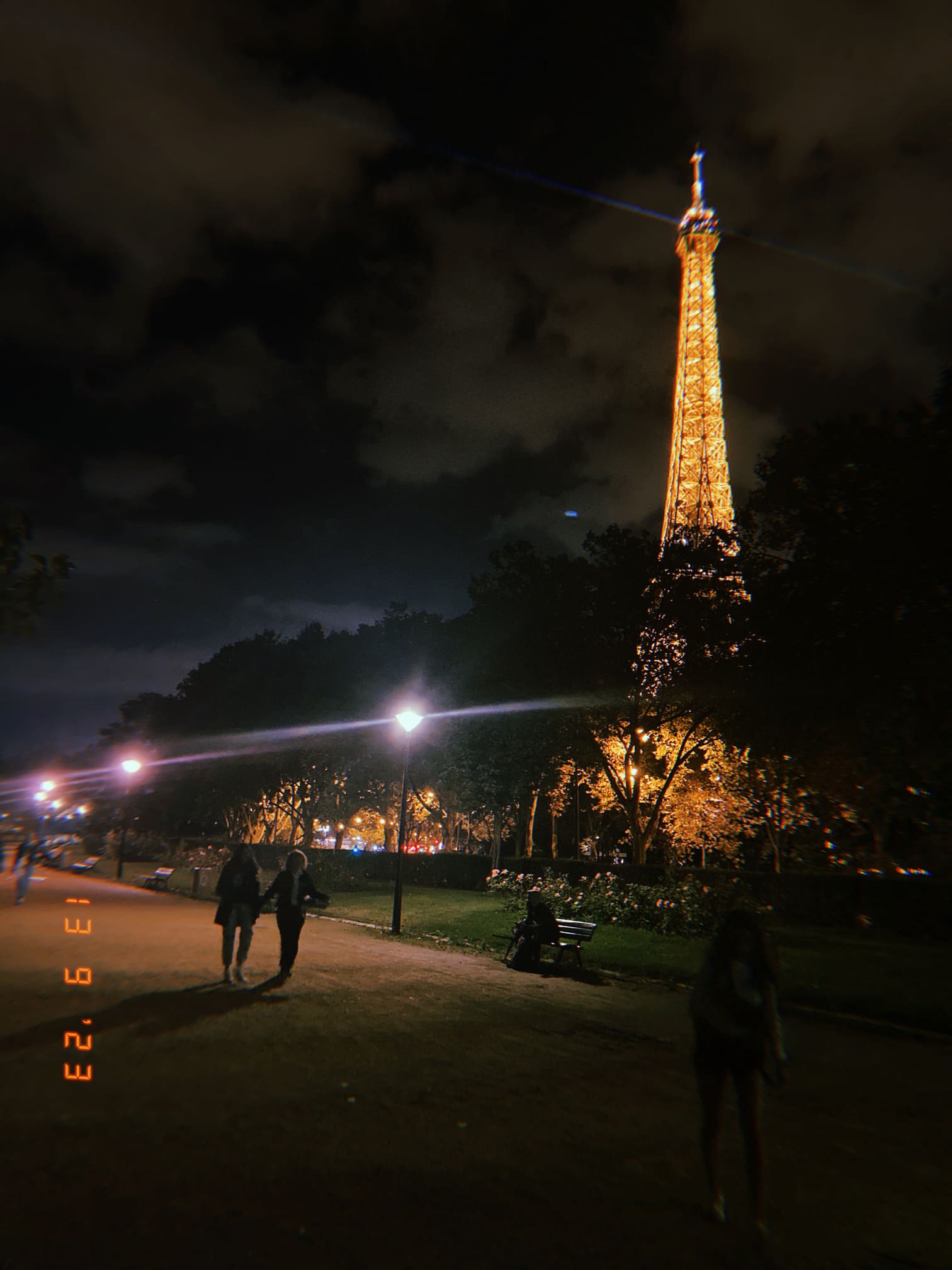 夜にライトアップされたエッフェル塔と公園の遊歩道