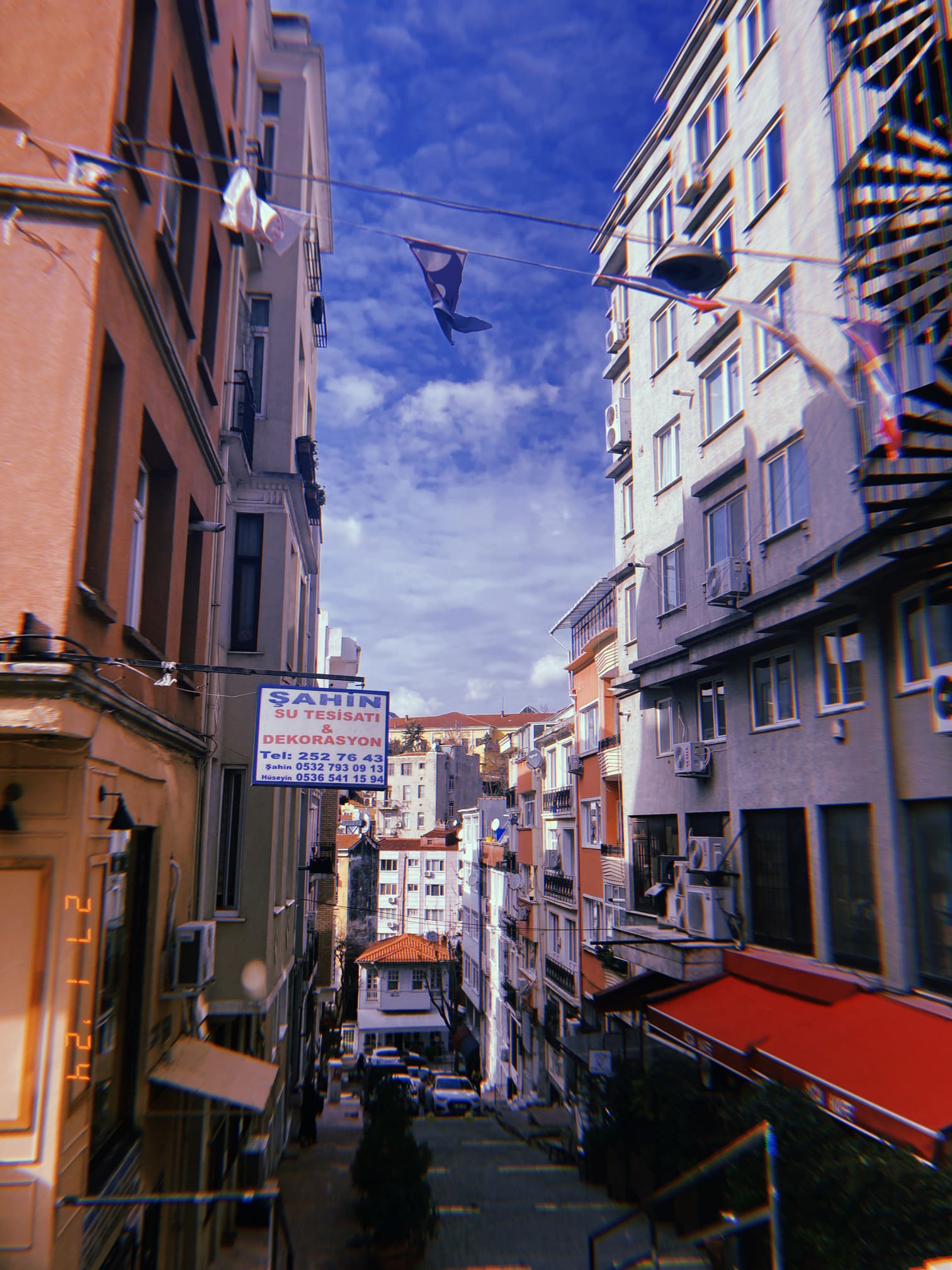 坂道の上で風に揺れる旗と生活感のある街並み